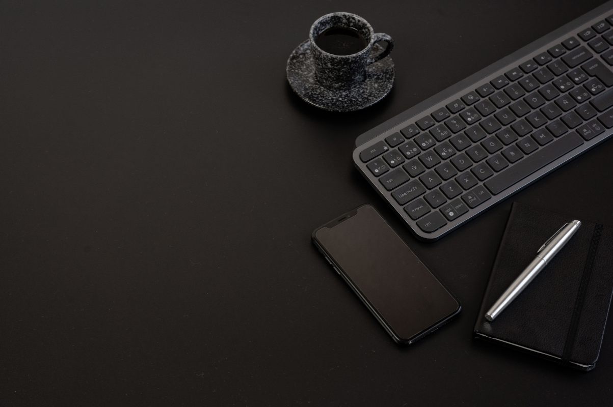 Dark desk with keyboard, phone and notebook, representing modern search research