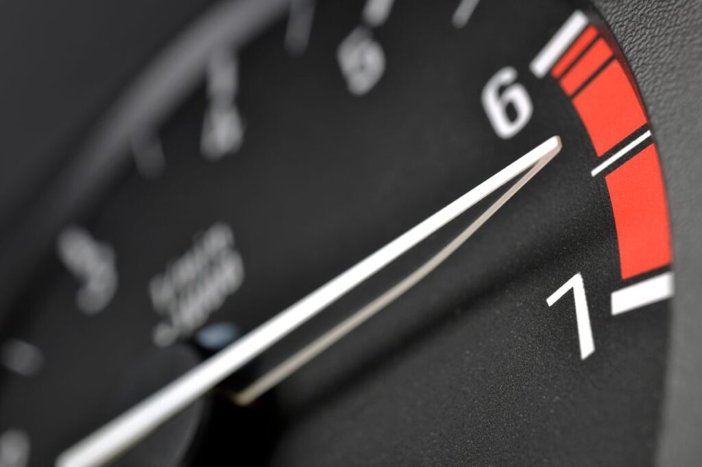 Close-up of a tachometer needle climbing into the red line, representing marketing performance