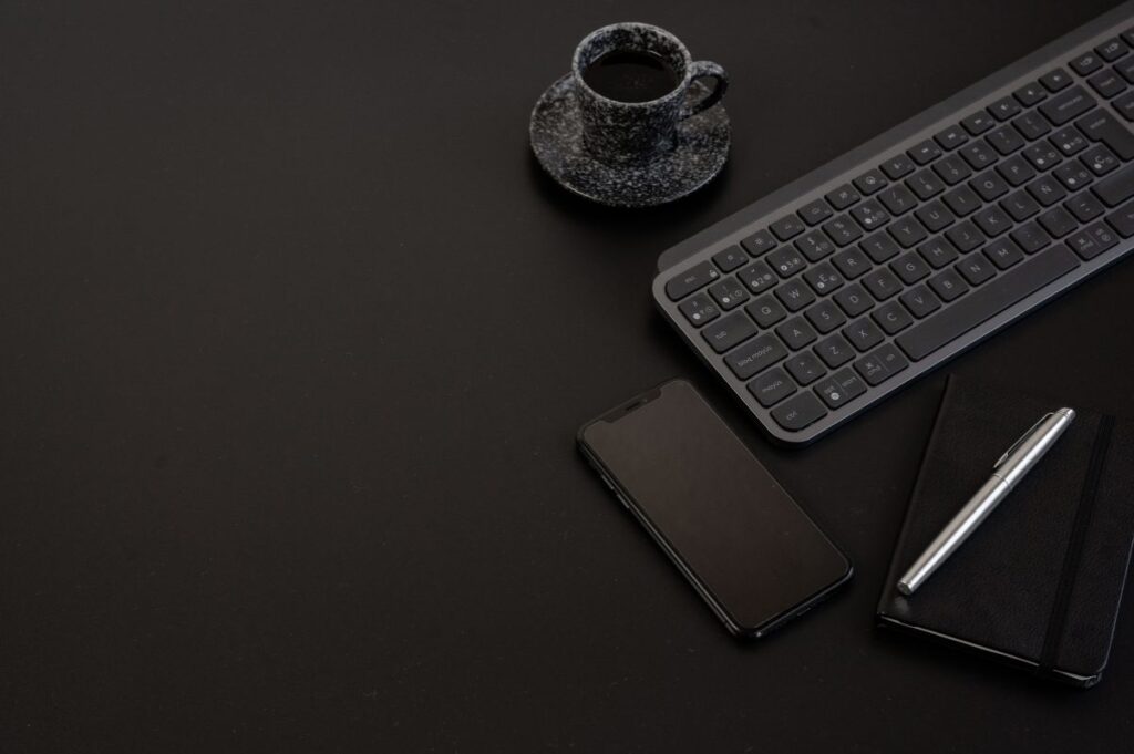 Dark desk with keyboard, phone and notebook, representing modern search research